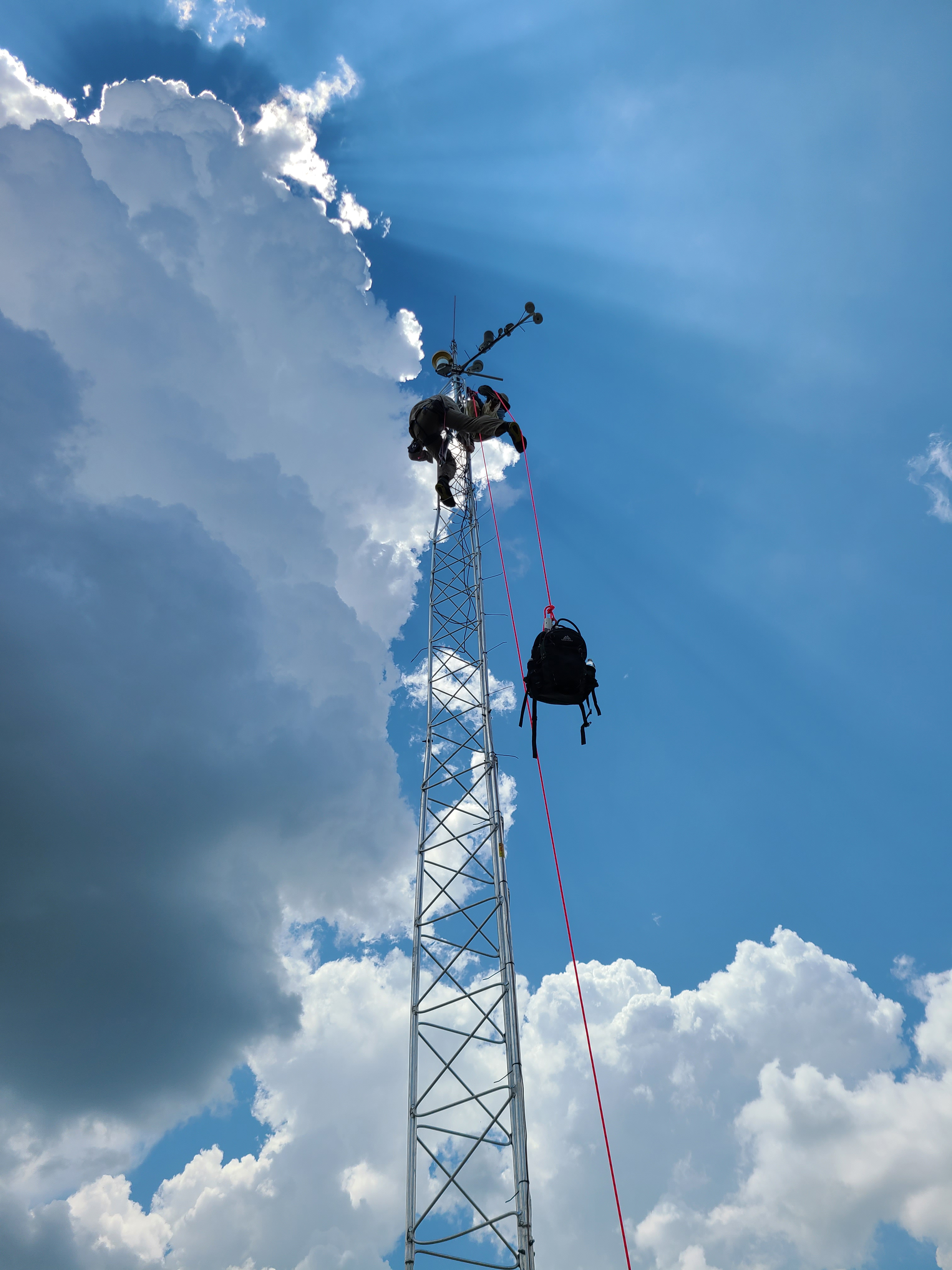 People climbing a flux tower on a clear day