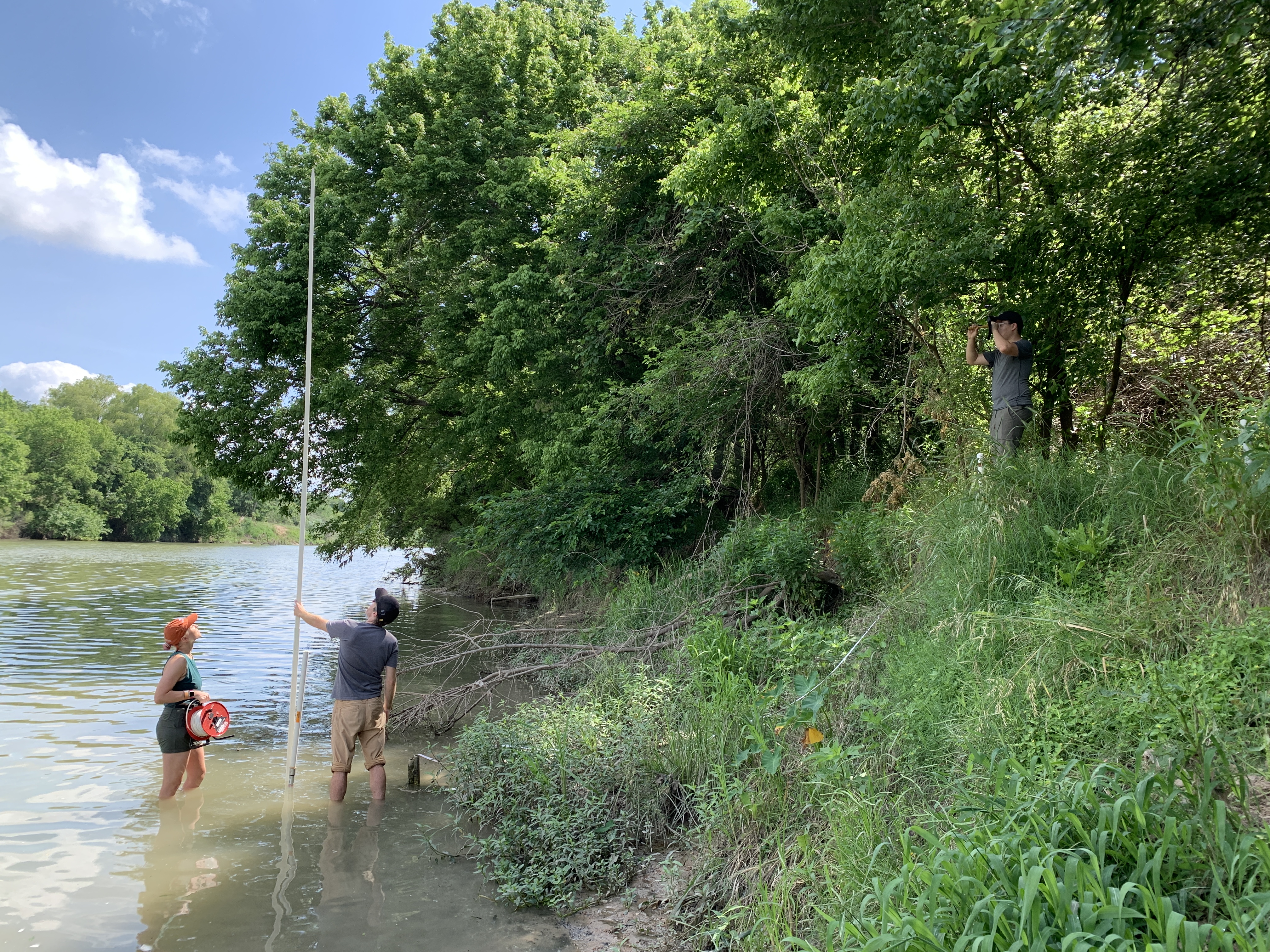 Two students standing in a lake measuring water depth