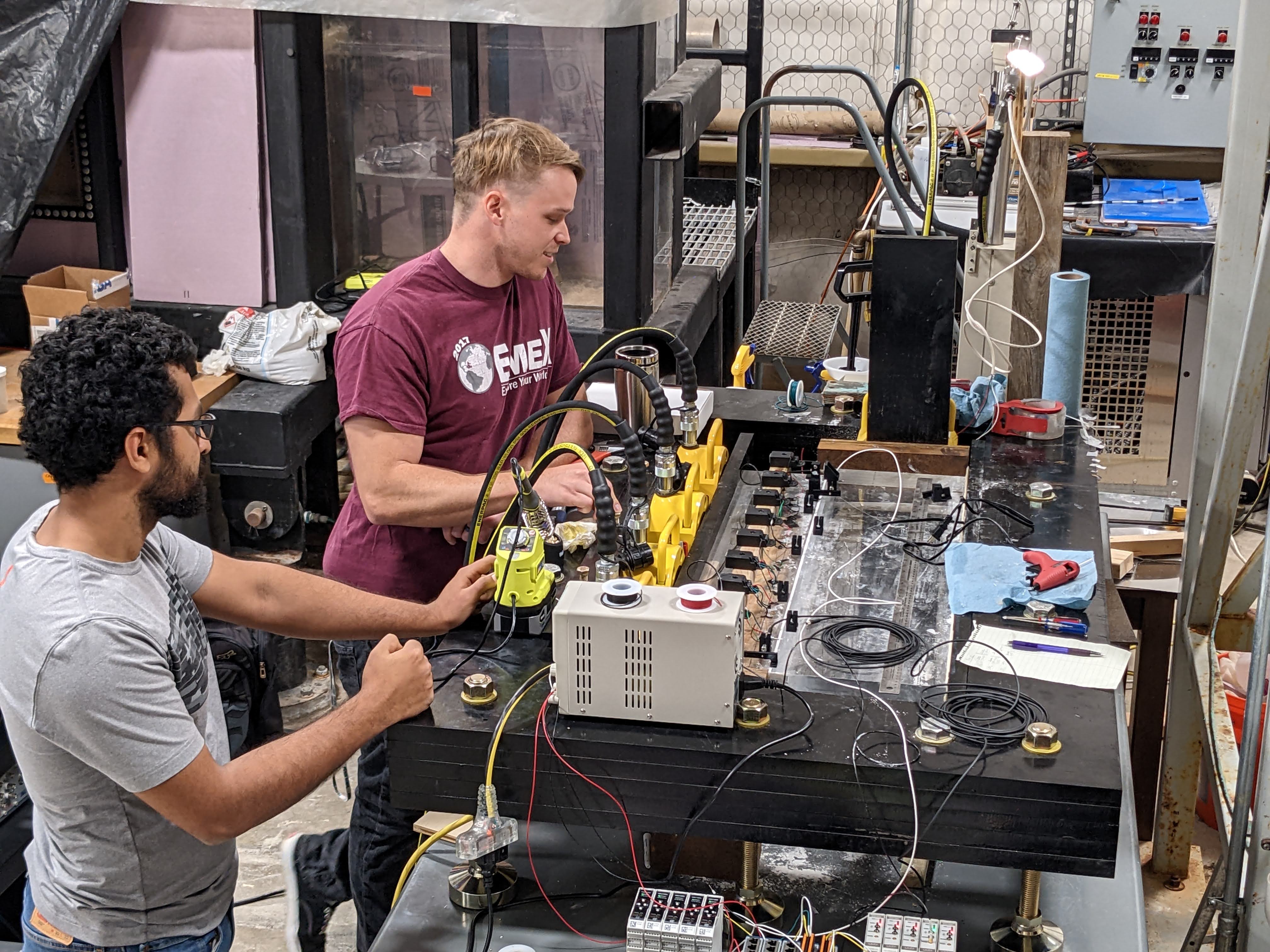 Two male students in an engineering lab working on a machine